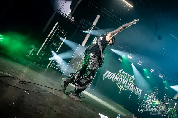 Singer on stage, arm raised under green and blue lights