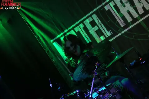 Drummer under green lasers in front of the band banner