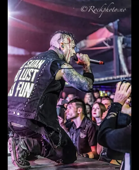 Singer kneeling at the barrier, singing to the front row