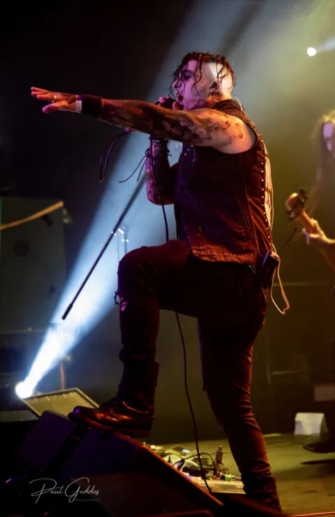 Singer pointing at the crowd, one foot on the monitor