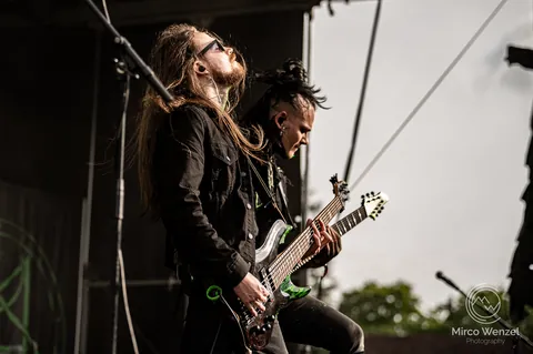 Guitarist and bassist side by side on an open air stage