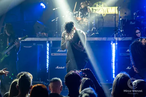 Singer in a white spotlight in front of a blue lit crowd