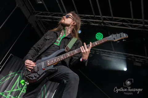 Bassist playing low under the festival truss